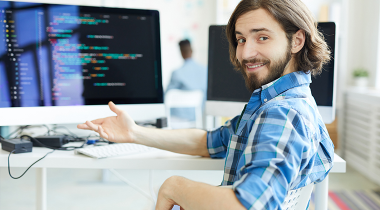 A SaaS company employee smiles at his computer after successfully white labeling a new solution. 