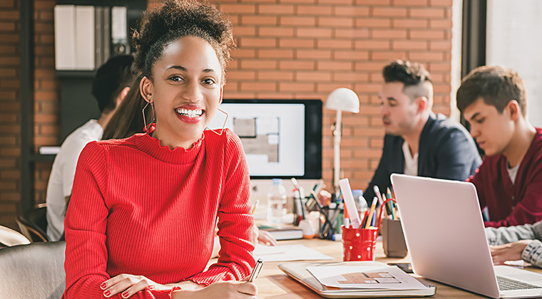 A startup professional smiles after finding the new feature that will help her company stand out amid their competition. 