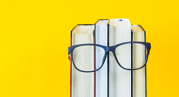 Row of four books with a pair of glasses placed across