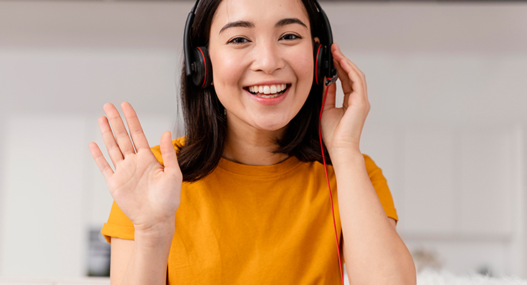 Smiling woman wearing headphones and waving to screen