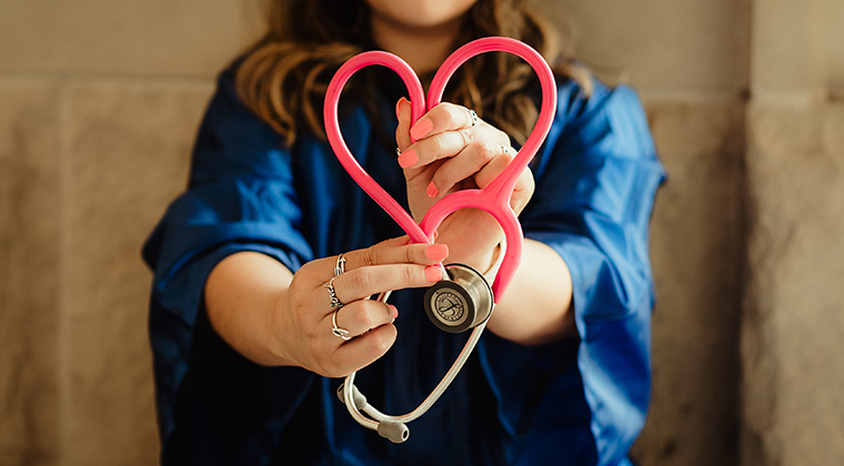 Healthcare worker holds up stethoscope in the shape of a heart