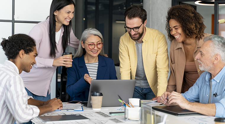 Employees at a people-forward workplace happily collaborate on a project. 