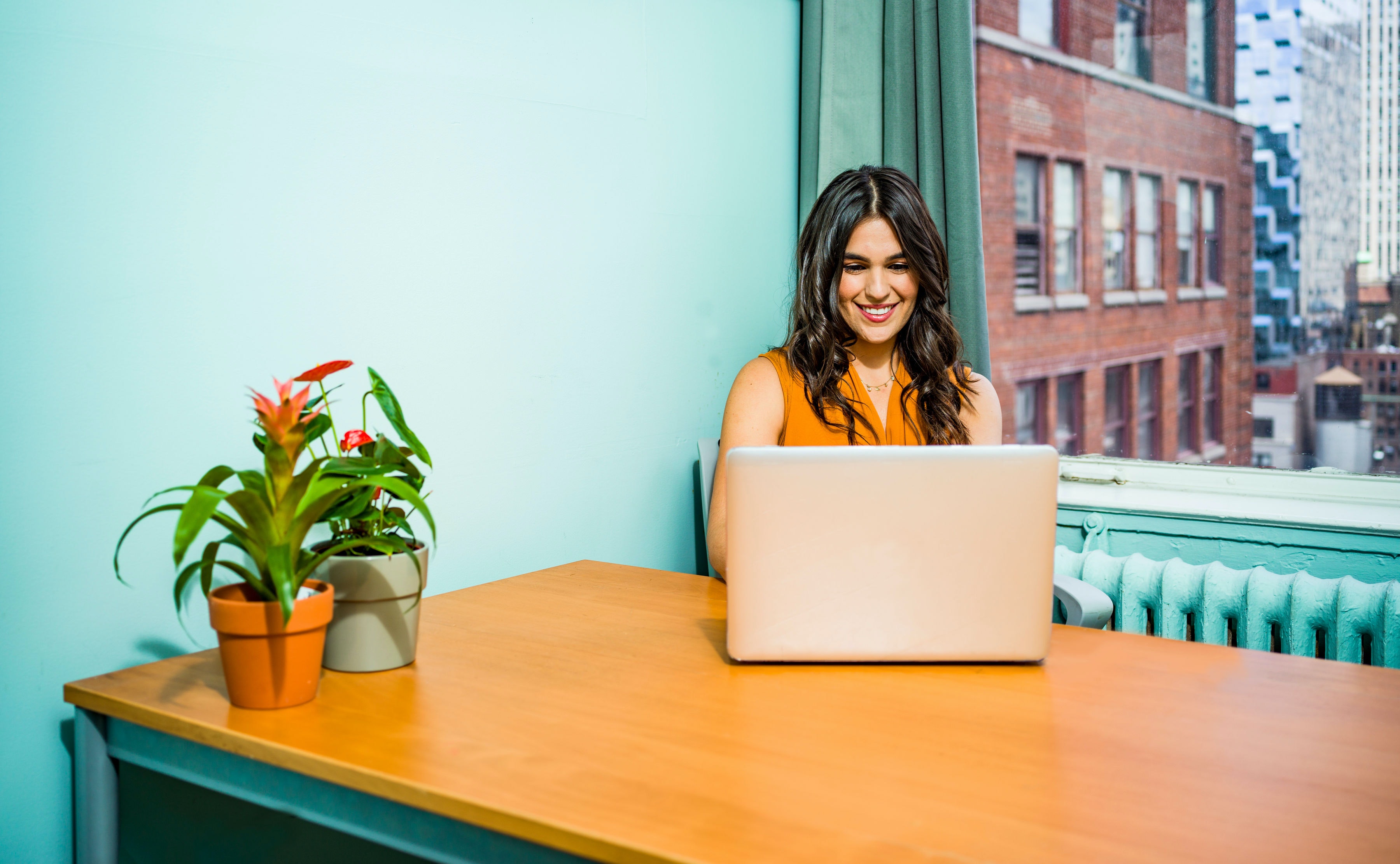 Smiling woman working at a desk with a laptop.