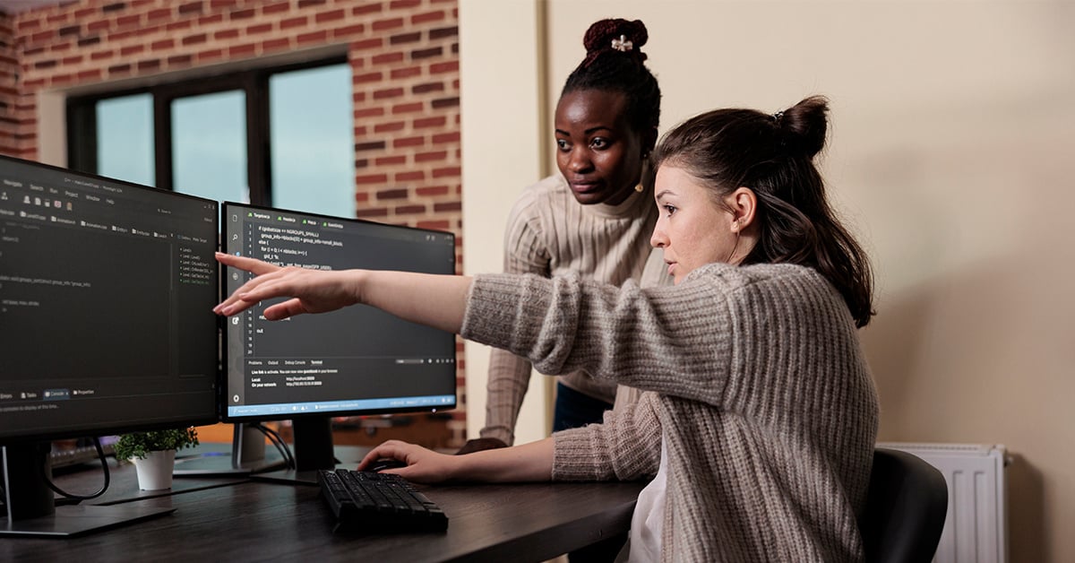 Engineer points at a problem on the screen while another looks over her shoulder