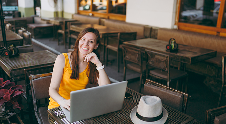 Smiling woman sitting in cafe with laptop