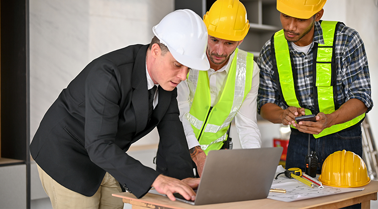Construction manager and workers review data on a computer