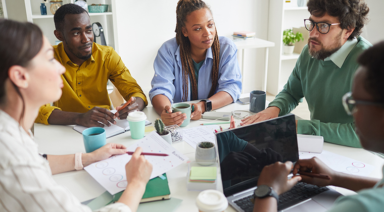 Diverse team meet around a table